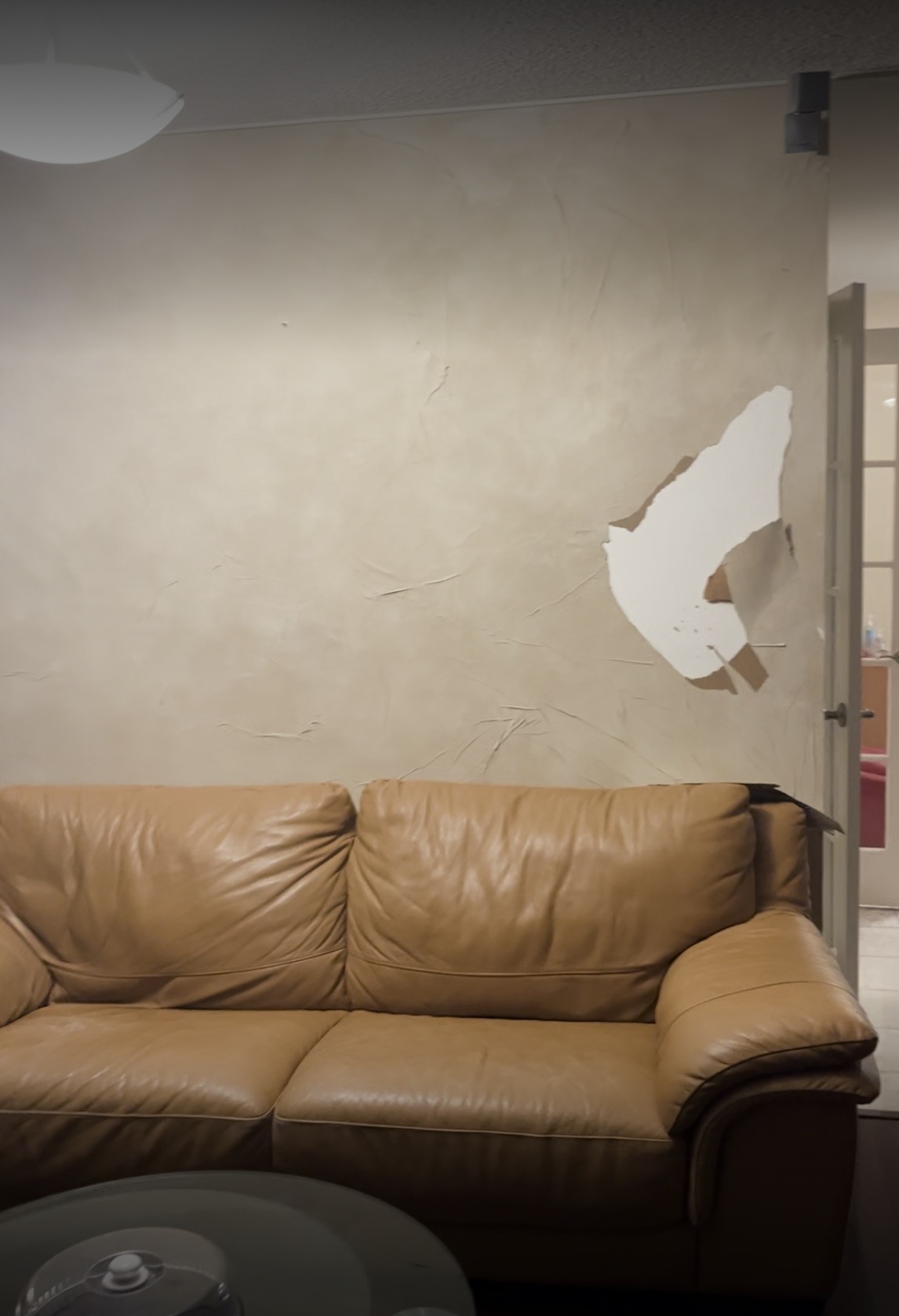 Original wall damage above the leather sofa before repair